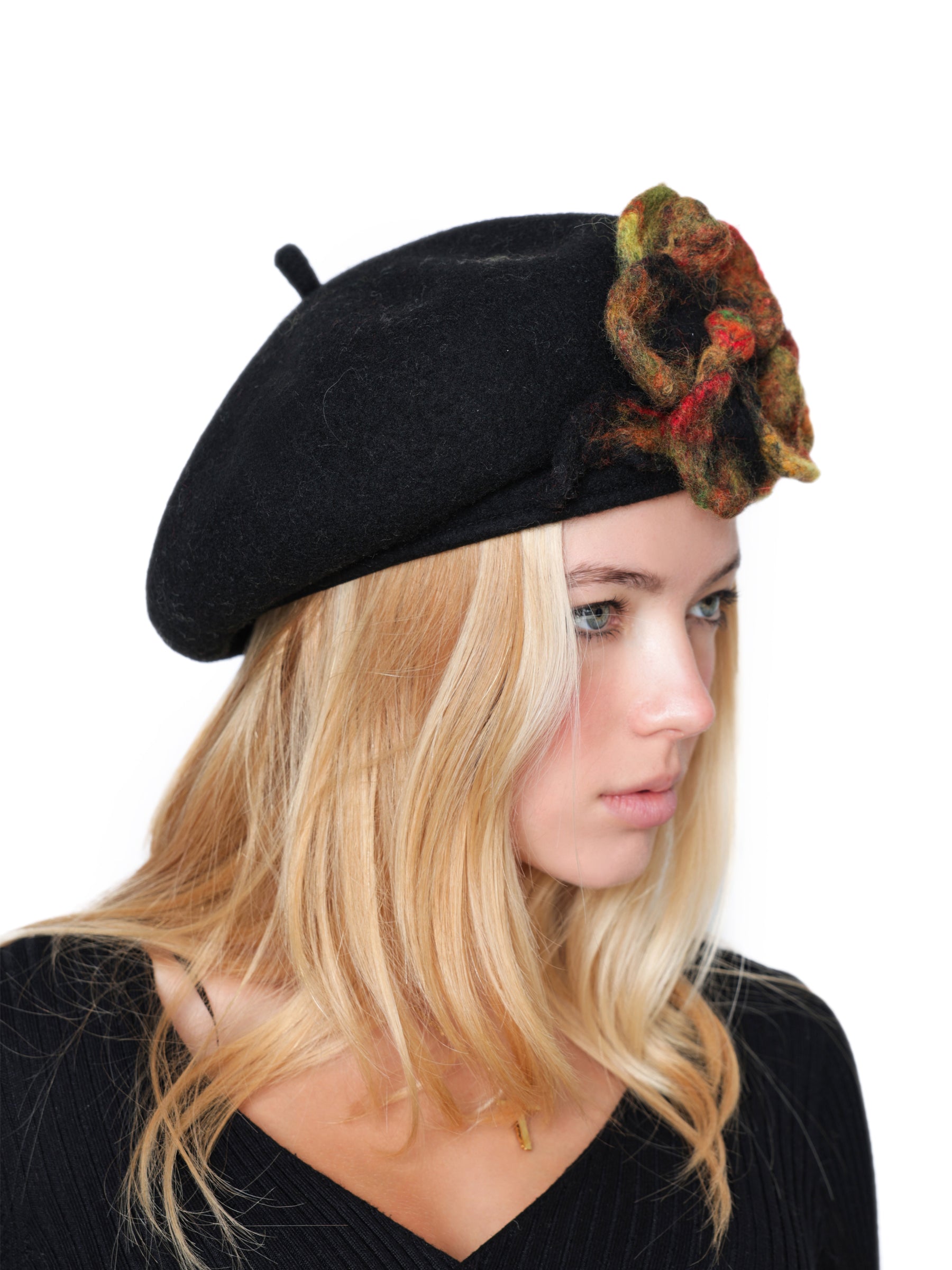 Side view of a black wool beret hat with textured handmade felt floral embellishment.