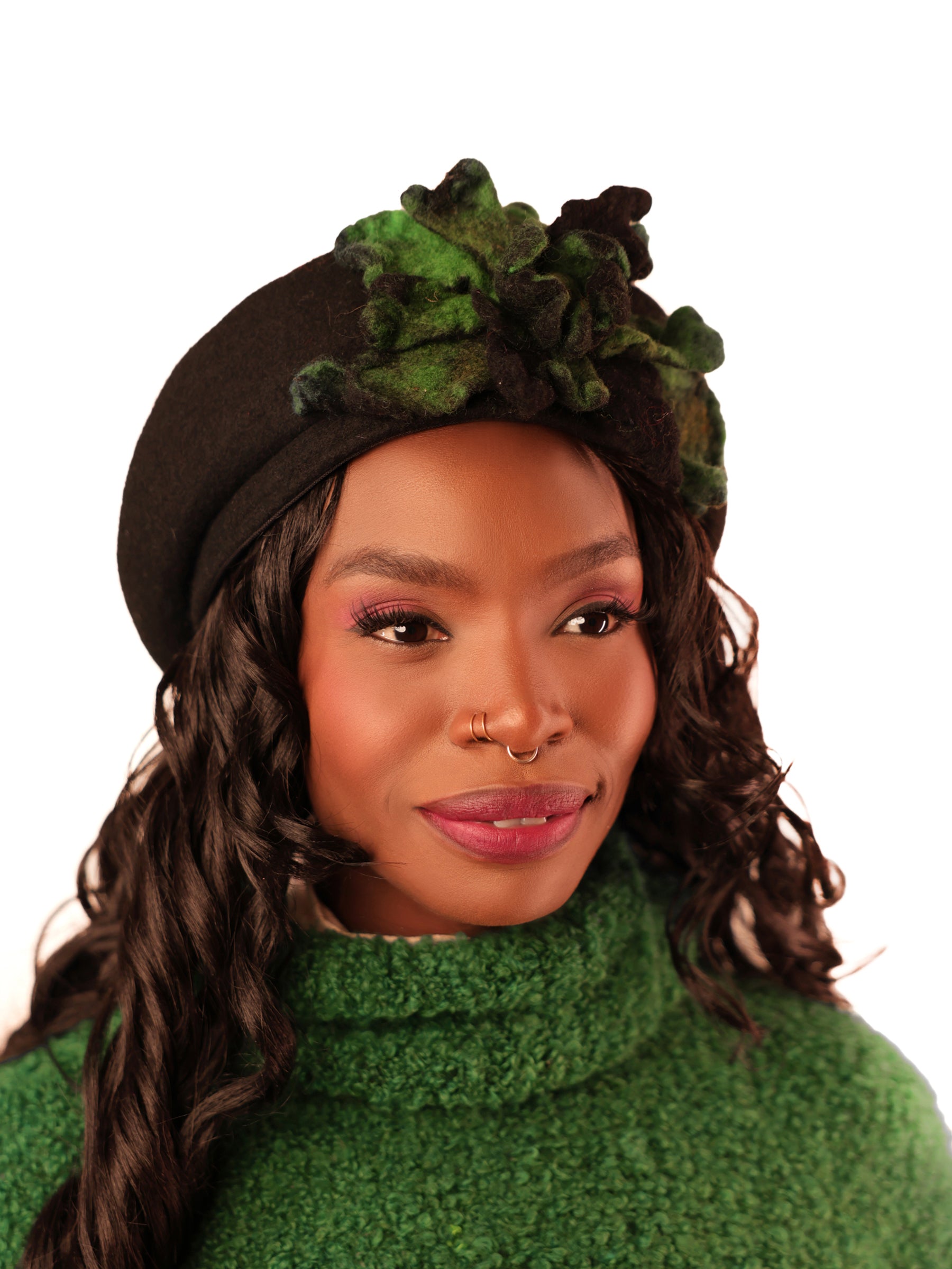 Black felted wool beret hat with green and grey floral detail, model looking slightly left, handcrafted winter beret.