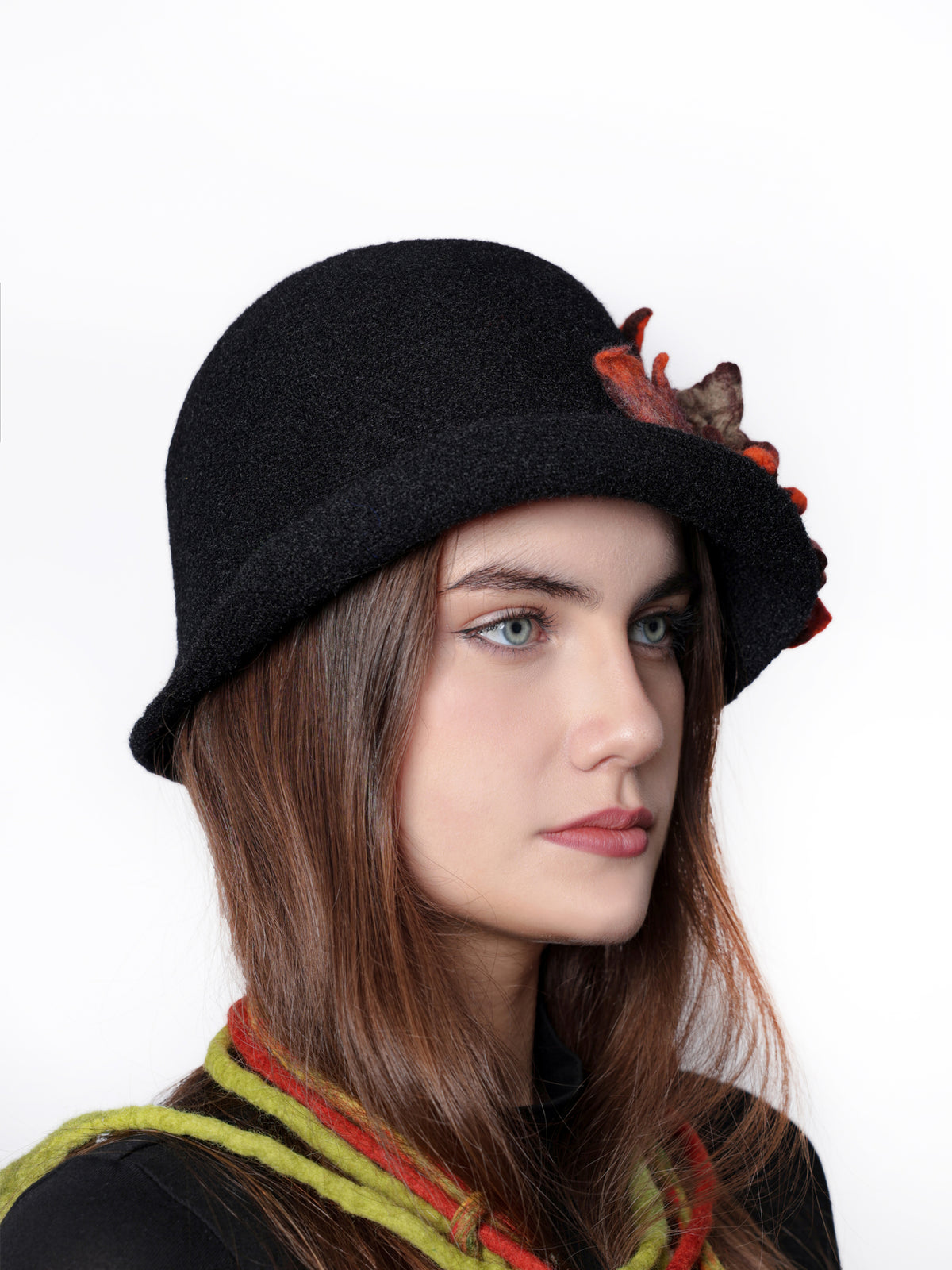 Angled view of a black cloche hat with textured handmade wool floral embellishment.
