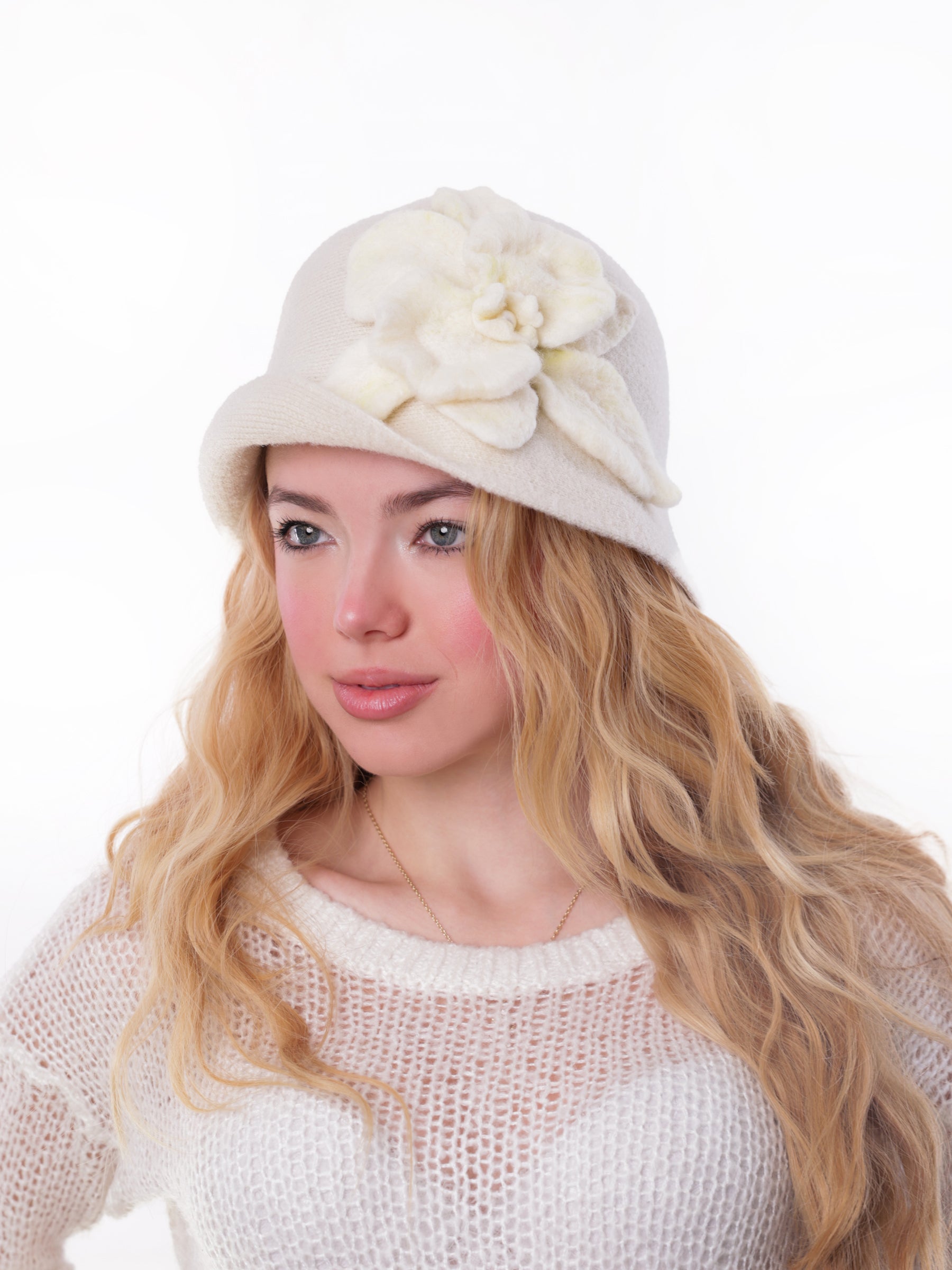 Angled side view of a white wool cloche hat featuring a handmade felt flower, worn by a woman.