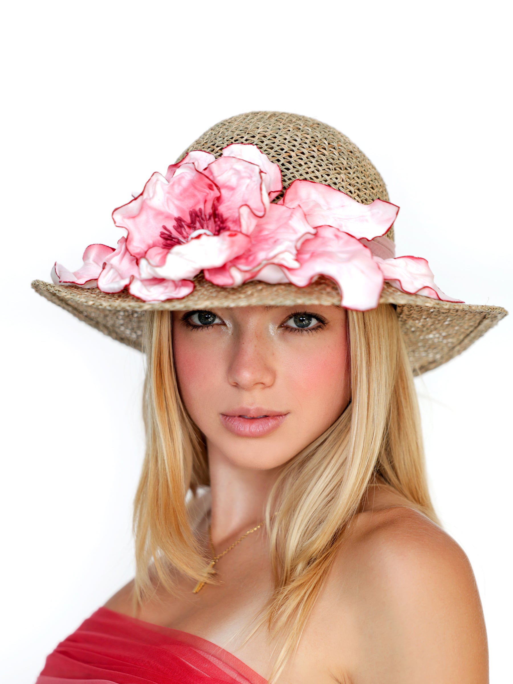 Front view of a straw summer hat featuring a handmade pink satin flower.