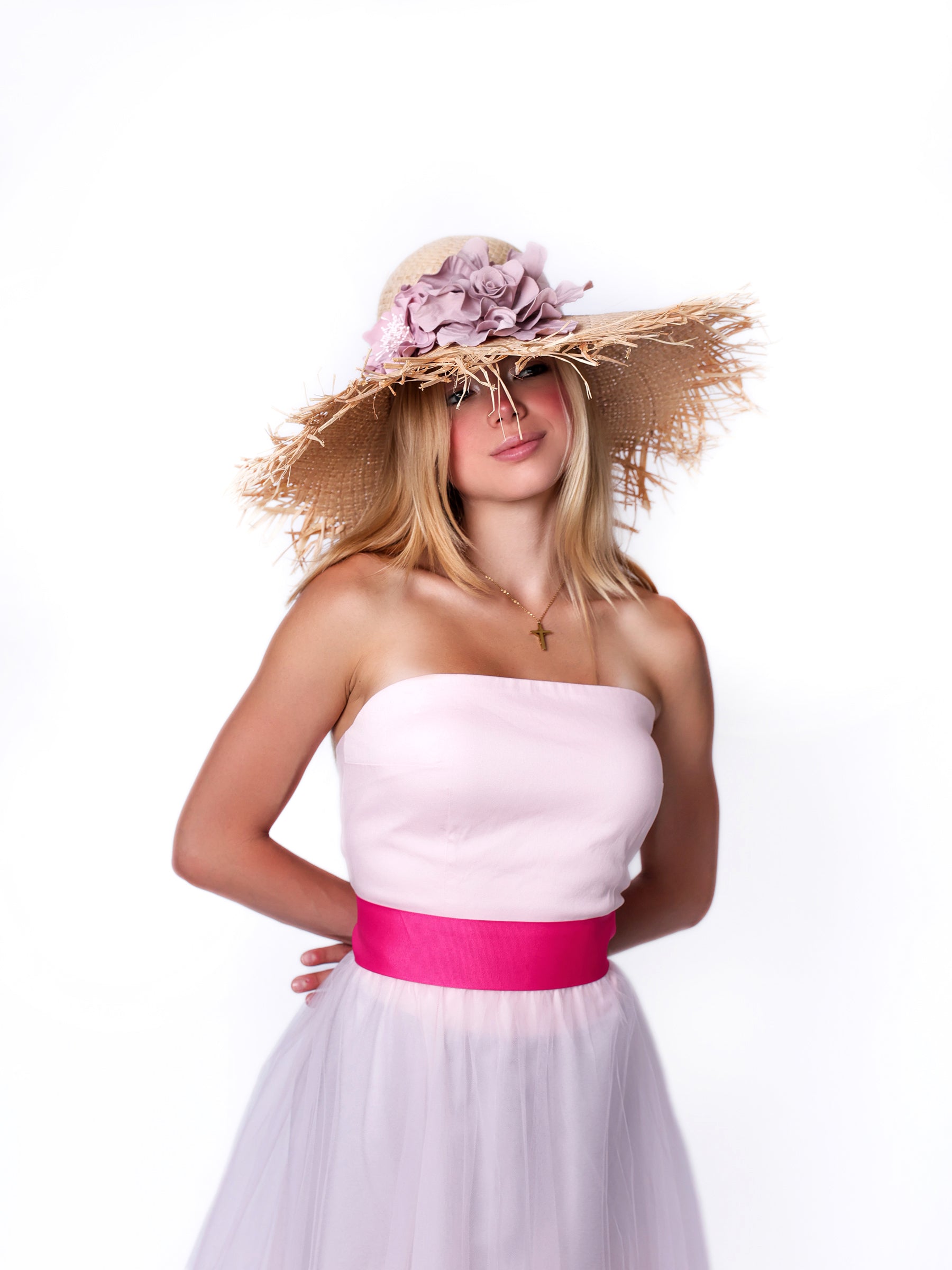 Model wearing a wide-brim straw summer sun hat with handmade pink satin floral detail, front view.