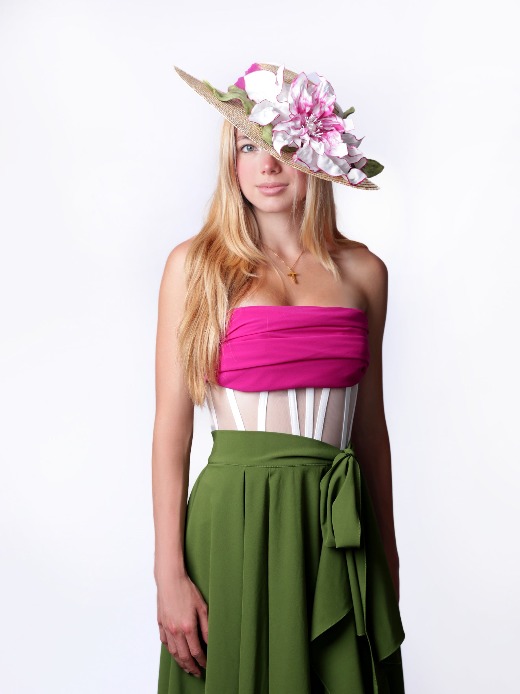 Model wearing a straw summer sun hat with handmade pink and white satin floral detail, angled view.