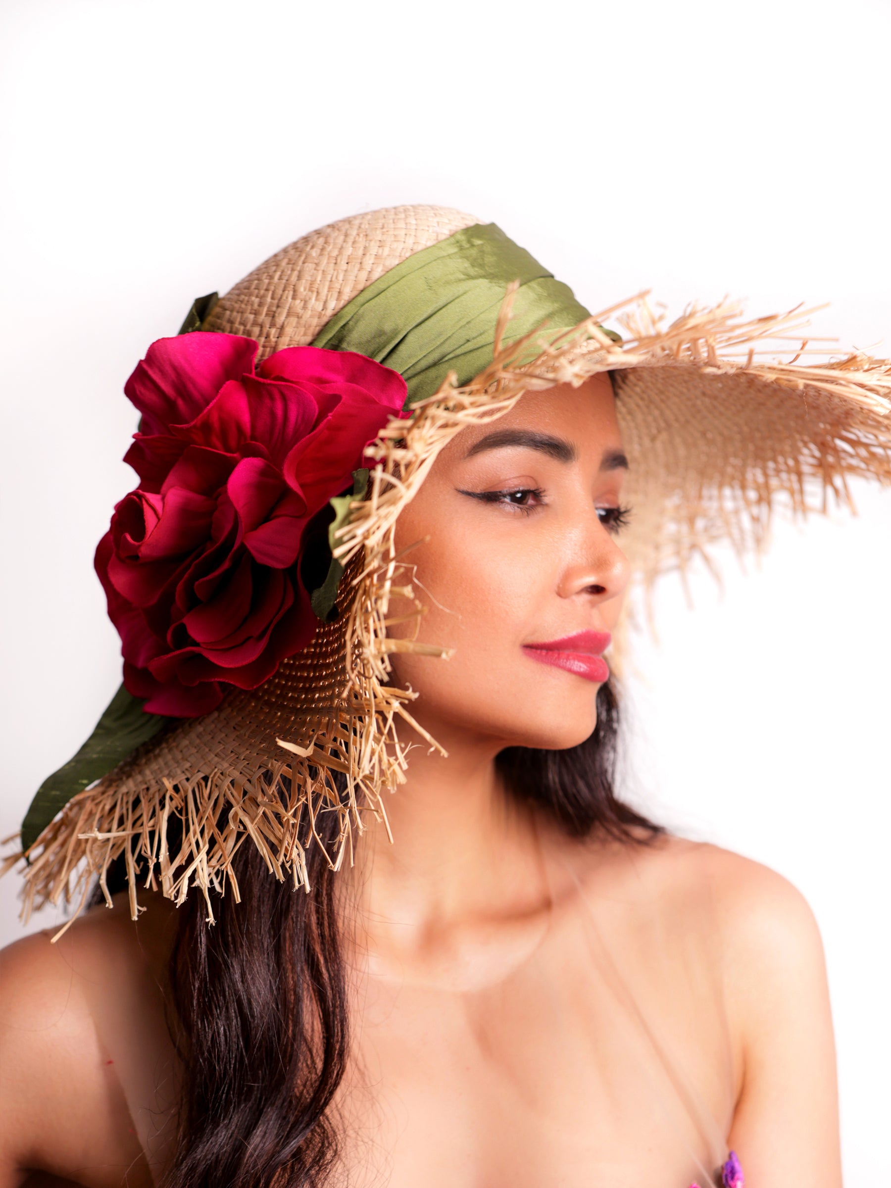 Side view of a straw summer sun hat with handmade red satin wild rose and green band detail.
