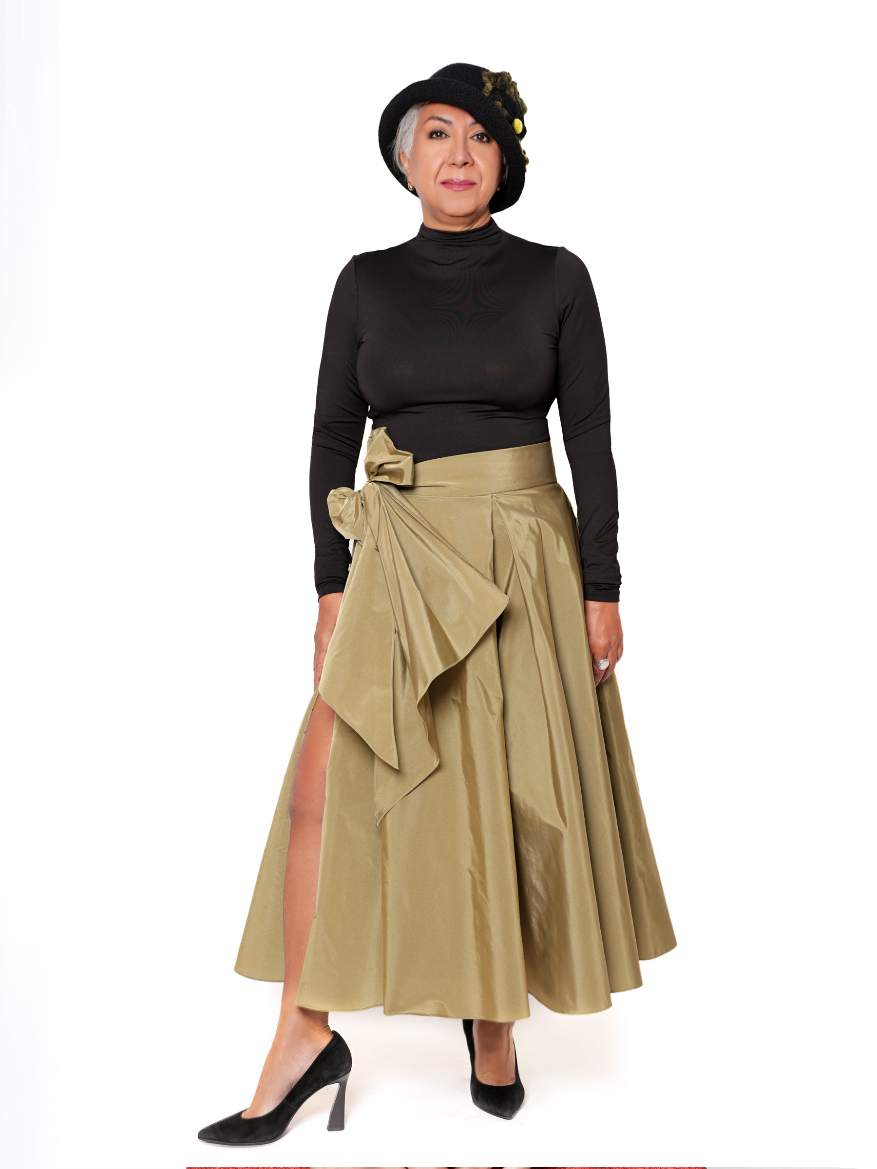Woman wearing an olive green handcrafted midi skirt with sculptural bow detail, designed and made in Canada.
