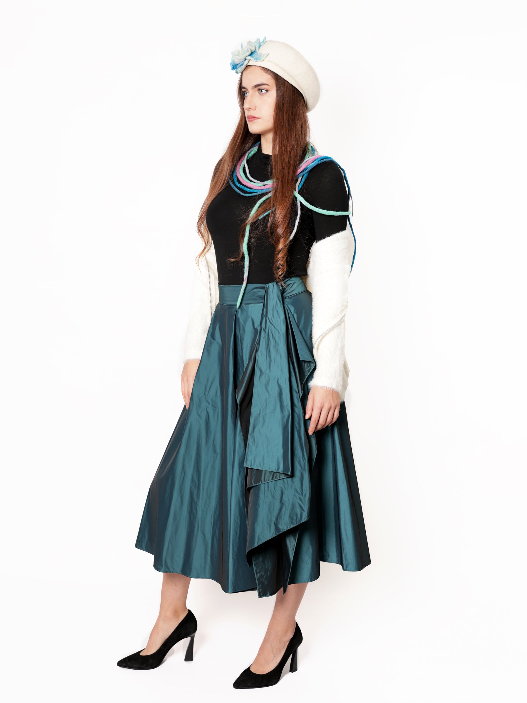 Woman modeling a handcrafted blue-teal midi skirt with graceful movement and refined sheen.
