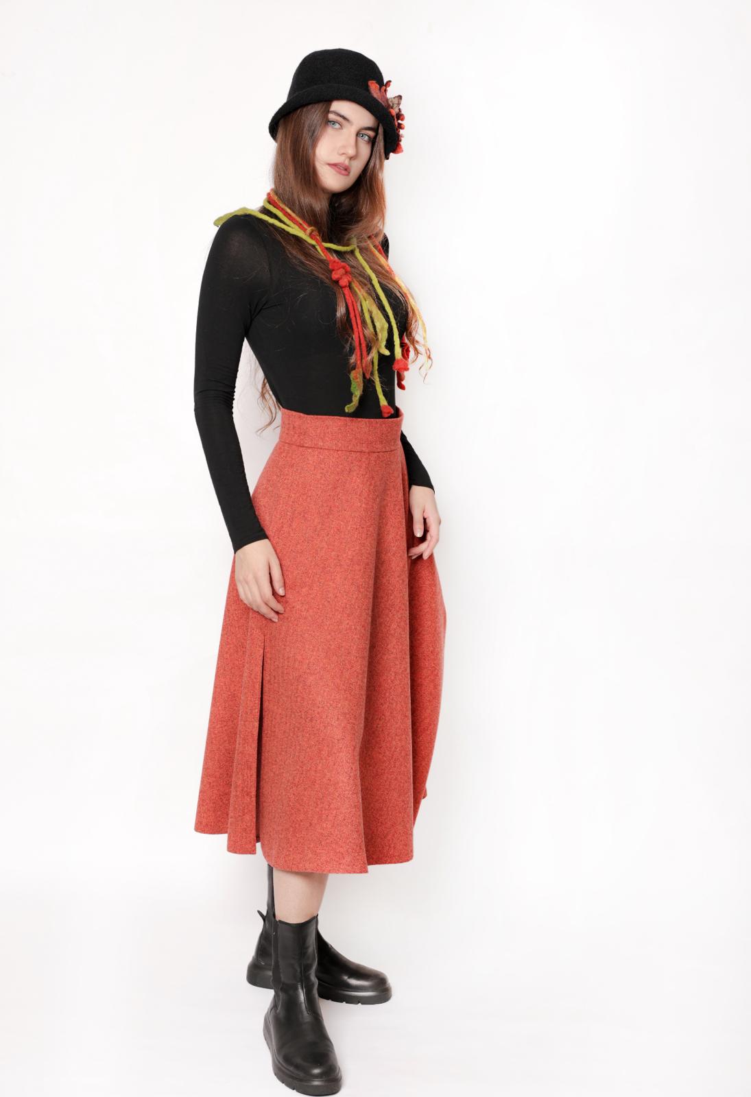 Woman wearing a handcrafted burnt orange midi skirt with red undertones, shown from head to toe in a side-angled pose.