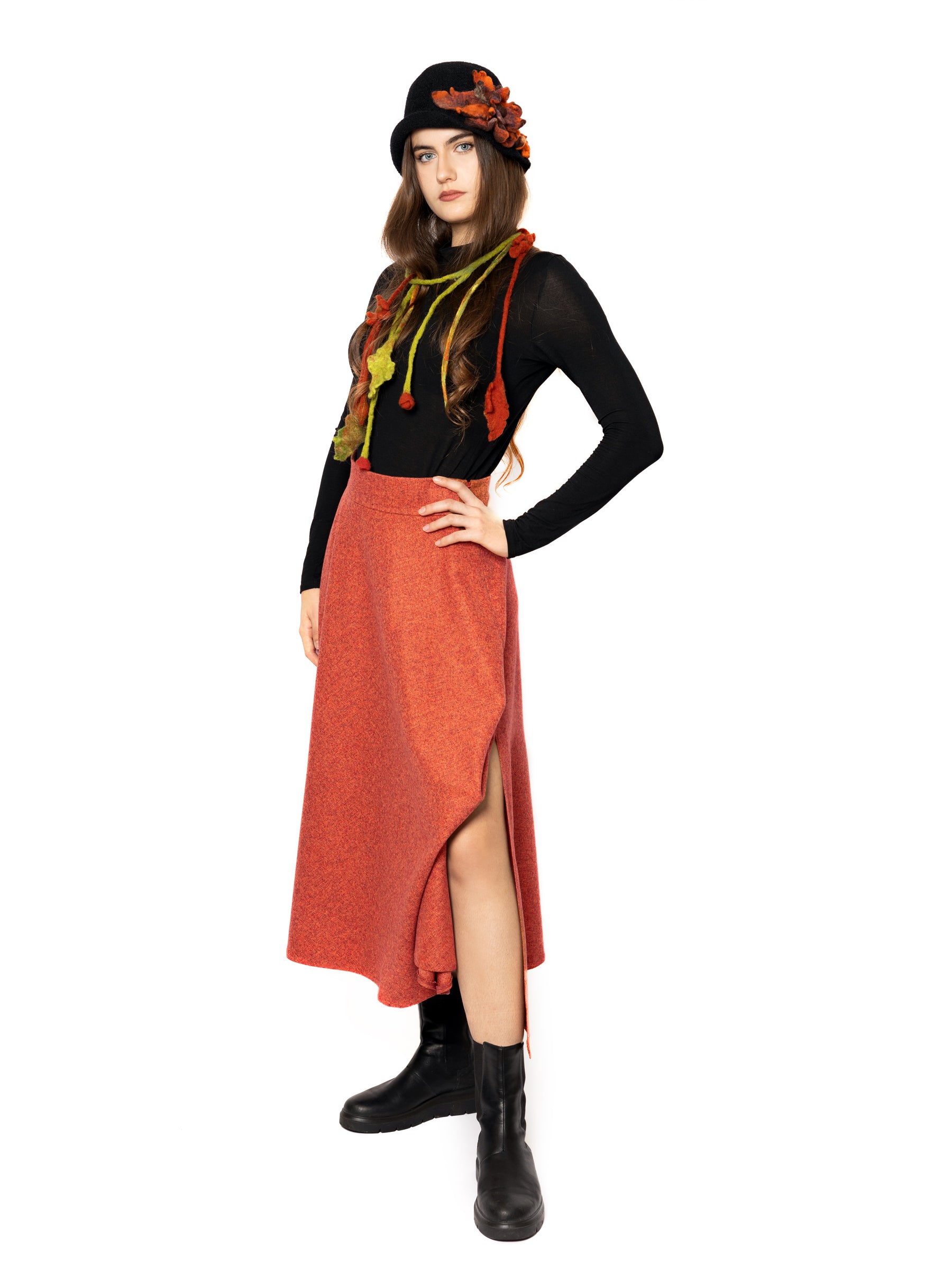 Female model wearing a handcrafted burnt orange and red-toned midi skirt from the side, highlighting its structured drape.
