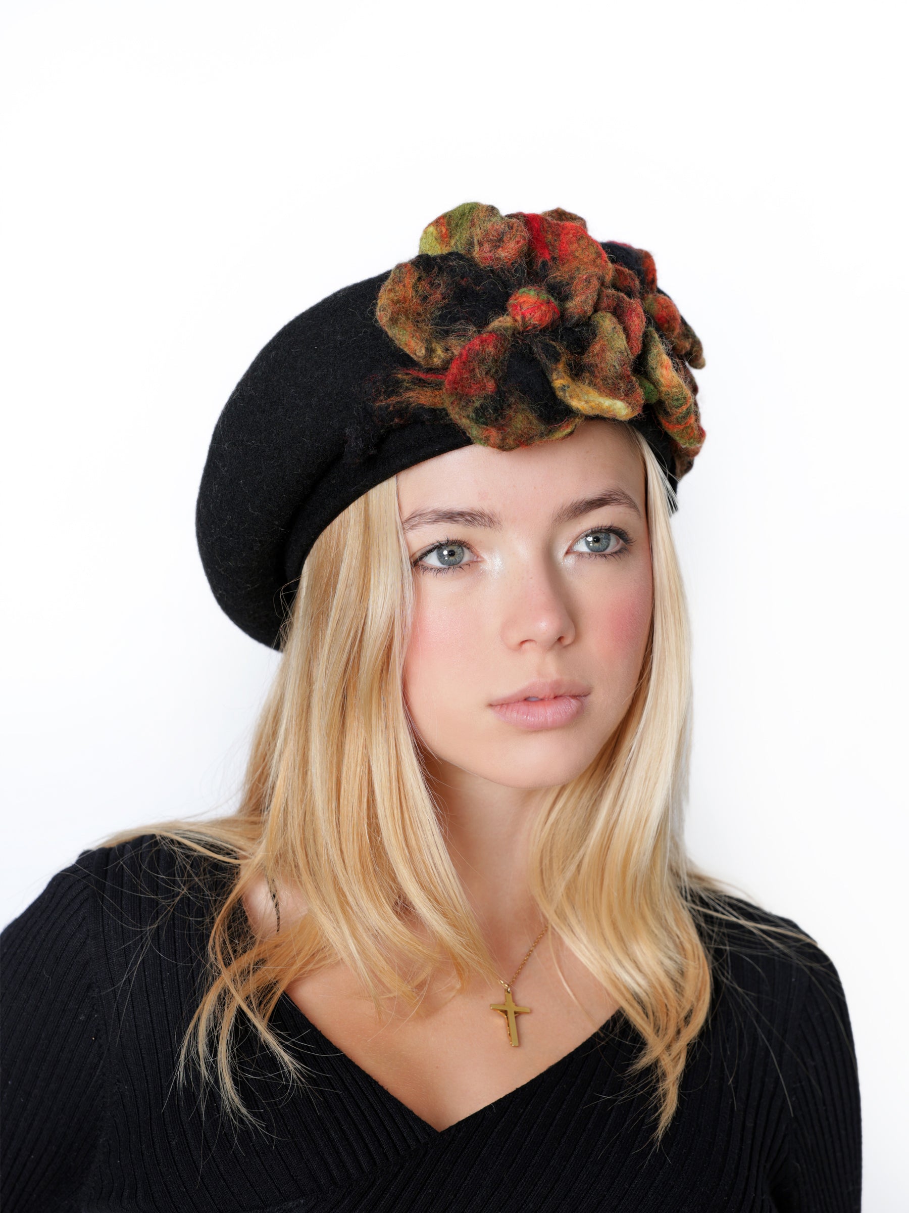 Angled view of a black wool beret hat with richly colored handmade felt flower detail.