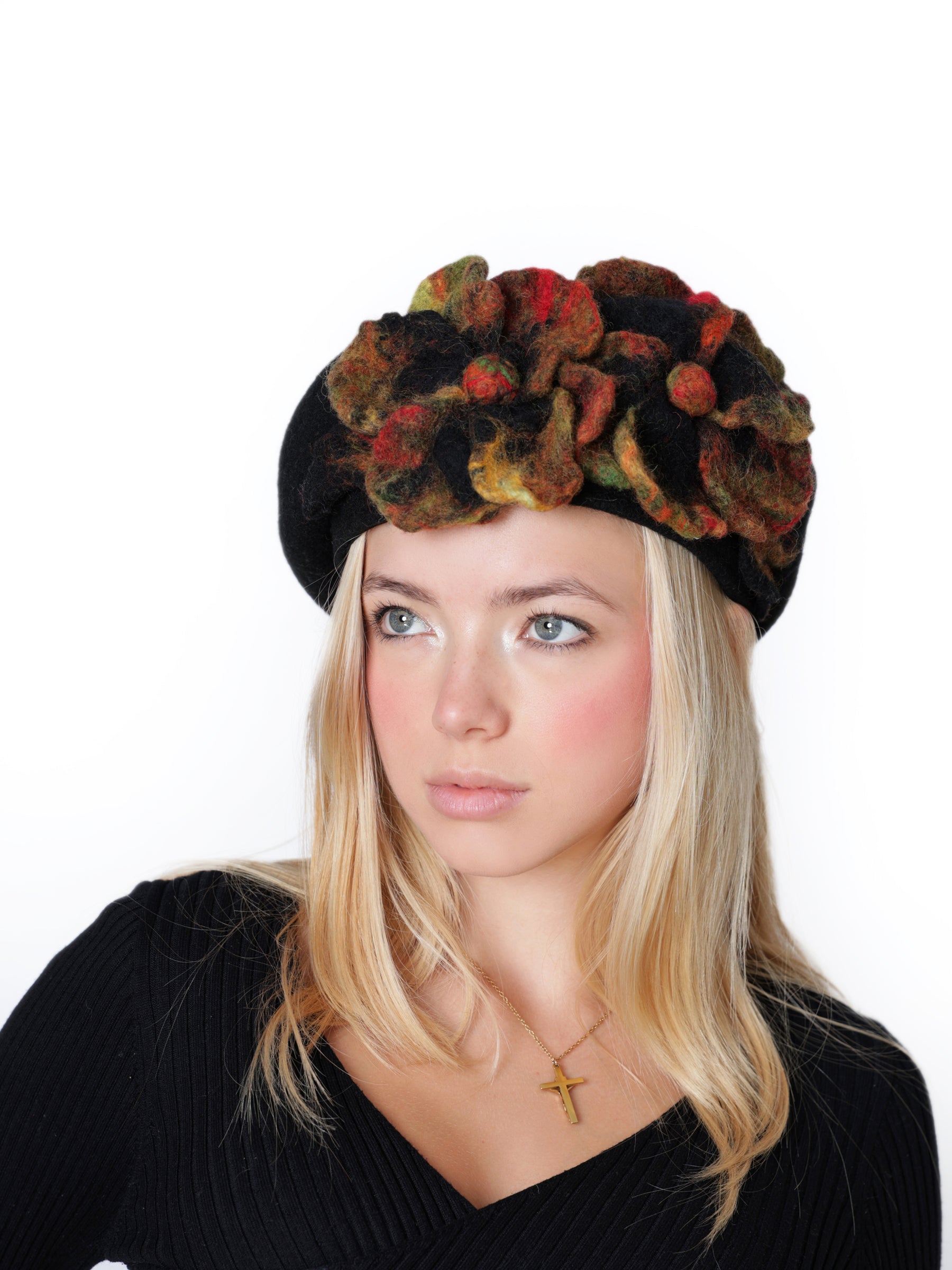 Close-up view of a black wool beret hat featuring a multitone felt flower in autumn colors.