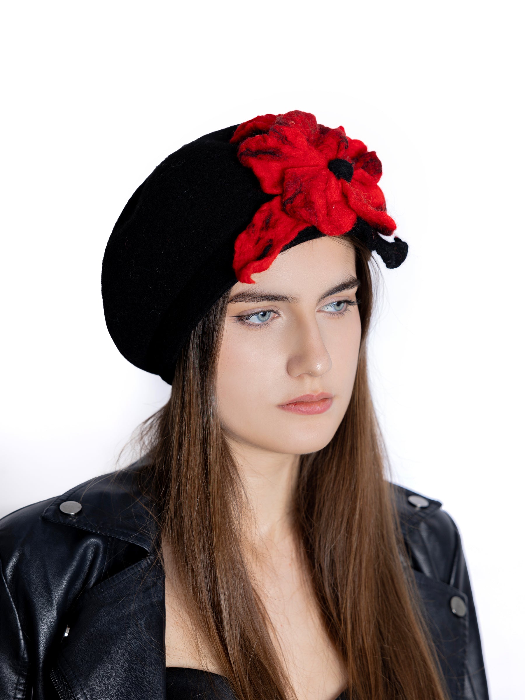 Model wearing a black wool beret hat with a handmade red felt flower, facing left.