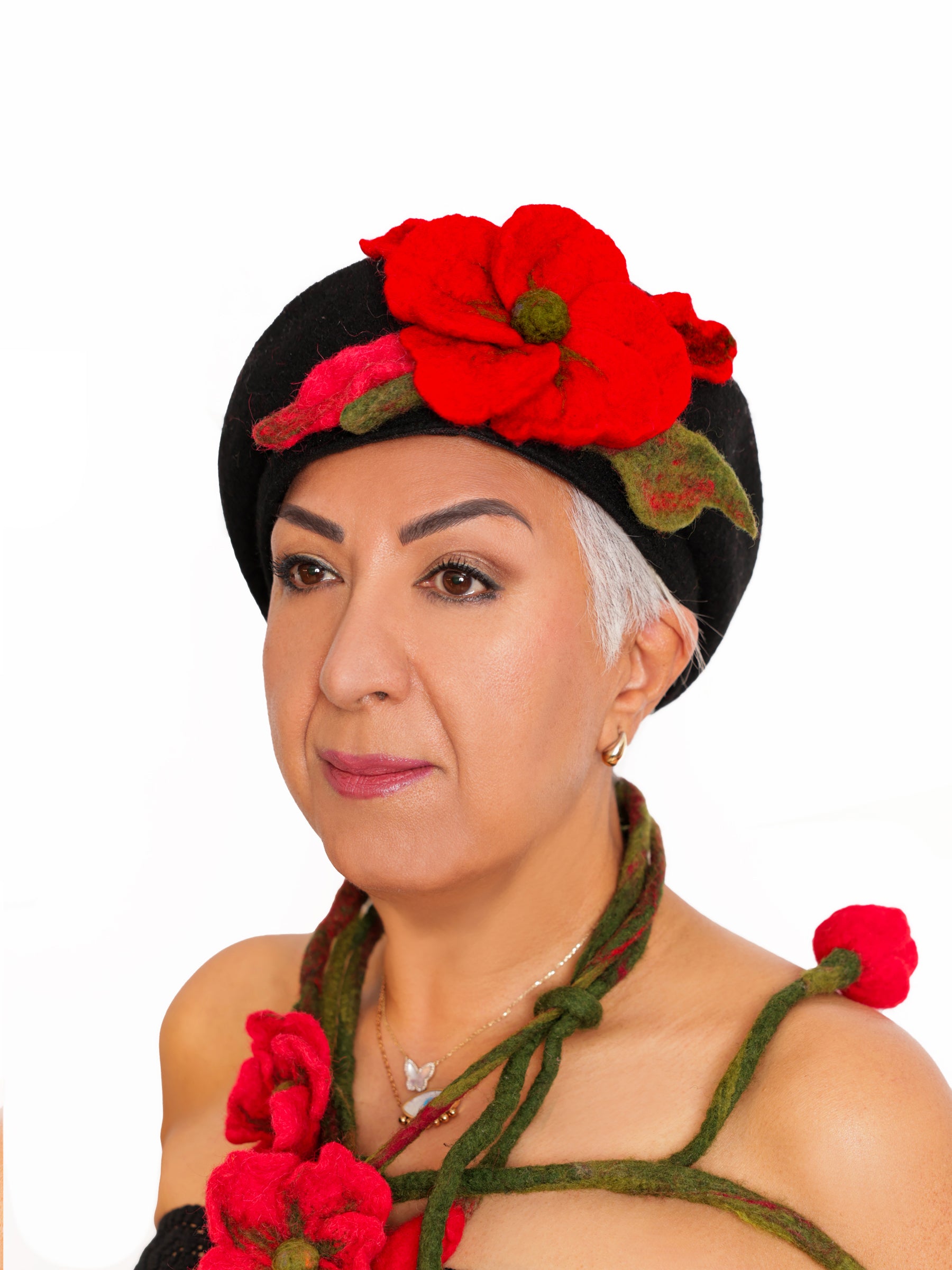 Side view of a woman wearing a handmade black wool beret with a sculptural red felt flower.