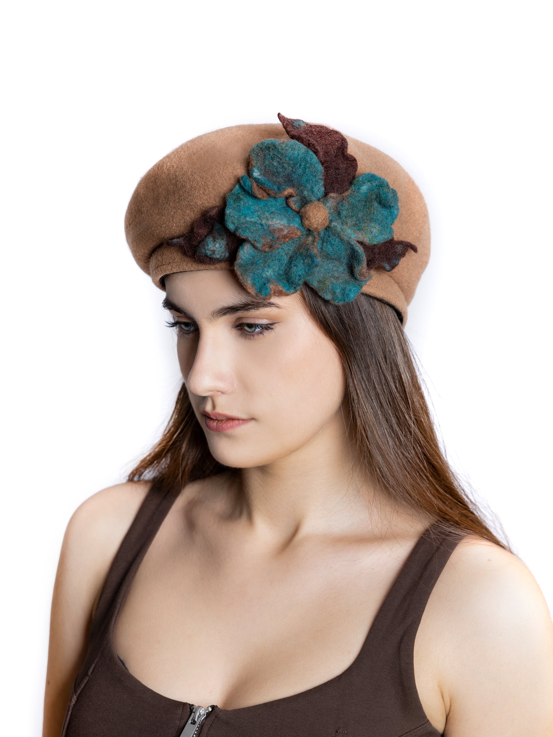 Close-up view of a wool beret hat with handmade felt flower and leaf embellishment.