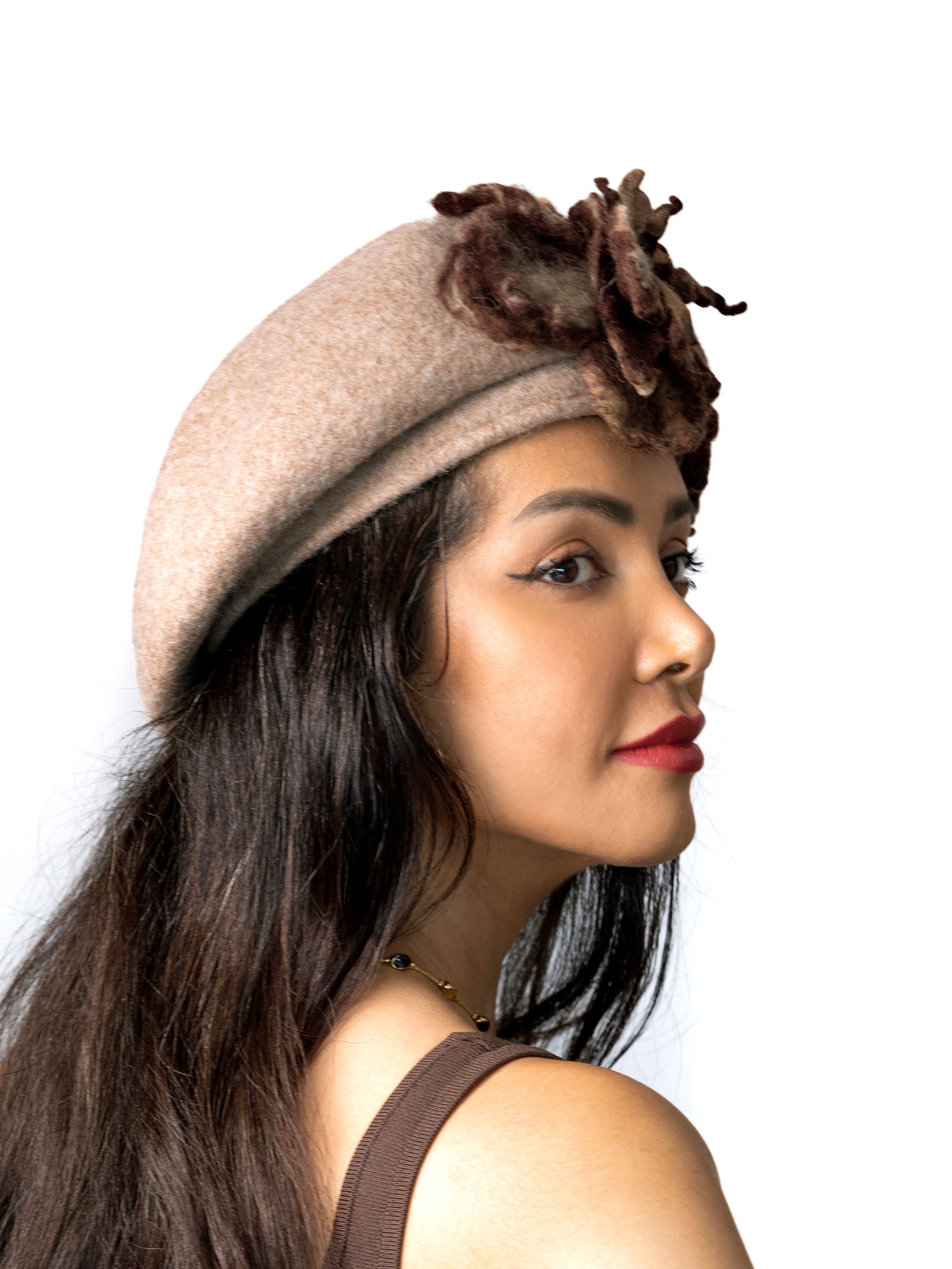 Side view of a wool winter beret hat featuring a sculptural brown felt flower in natural tones.