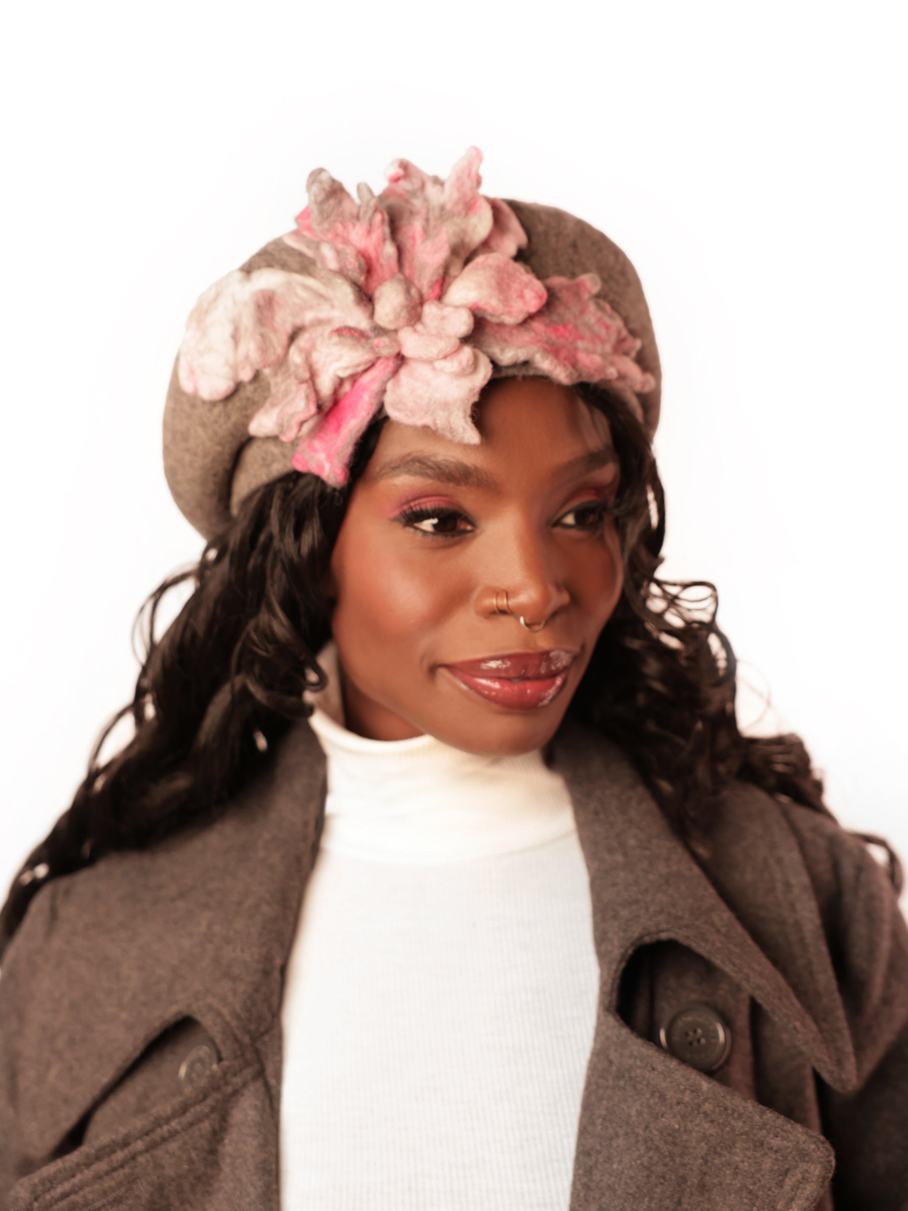 Side view of a grey wool winter hat featuring sculptural ash pink felt floral embellishment.