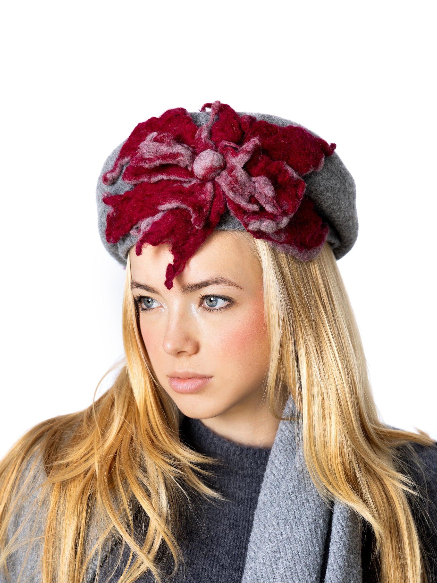 Side view of a grey wool beret hat featuring a sculptural handmade red felt flower.