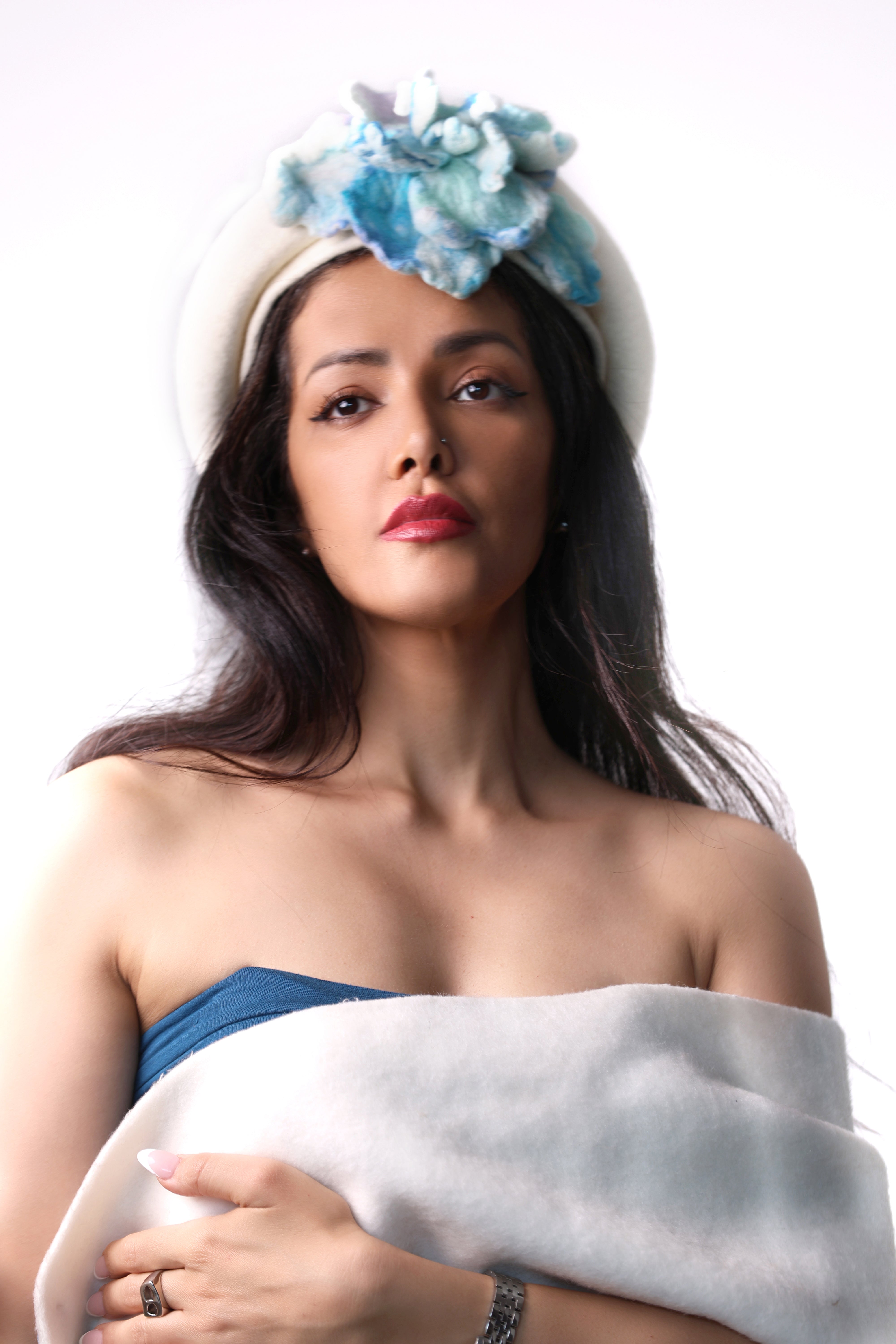 Front view of a white wool winter beret hat featuring a sculptural light blue felt flower.