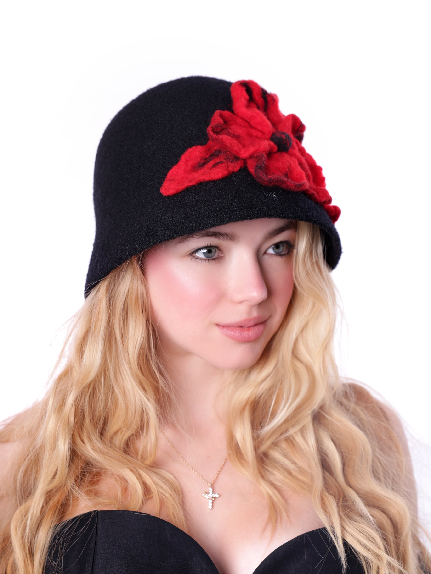 Side view of a woman wearing a handmade black cloche hat featuring a sculptural crimson wool flower.