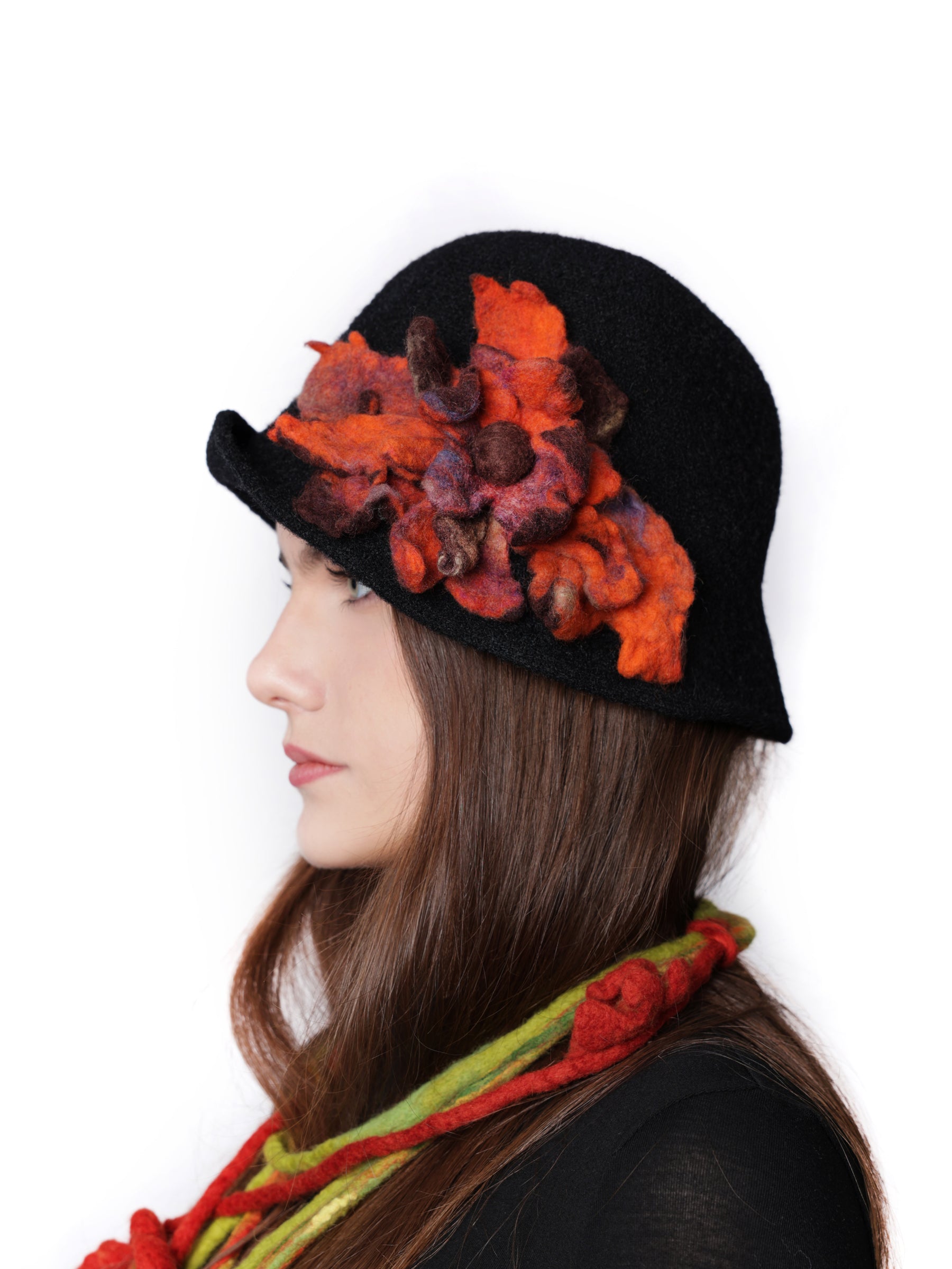 Side view of a black cloche hat featuring sculptural handmade wool flower details.