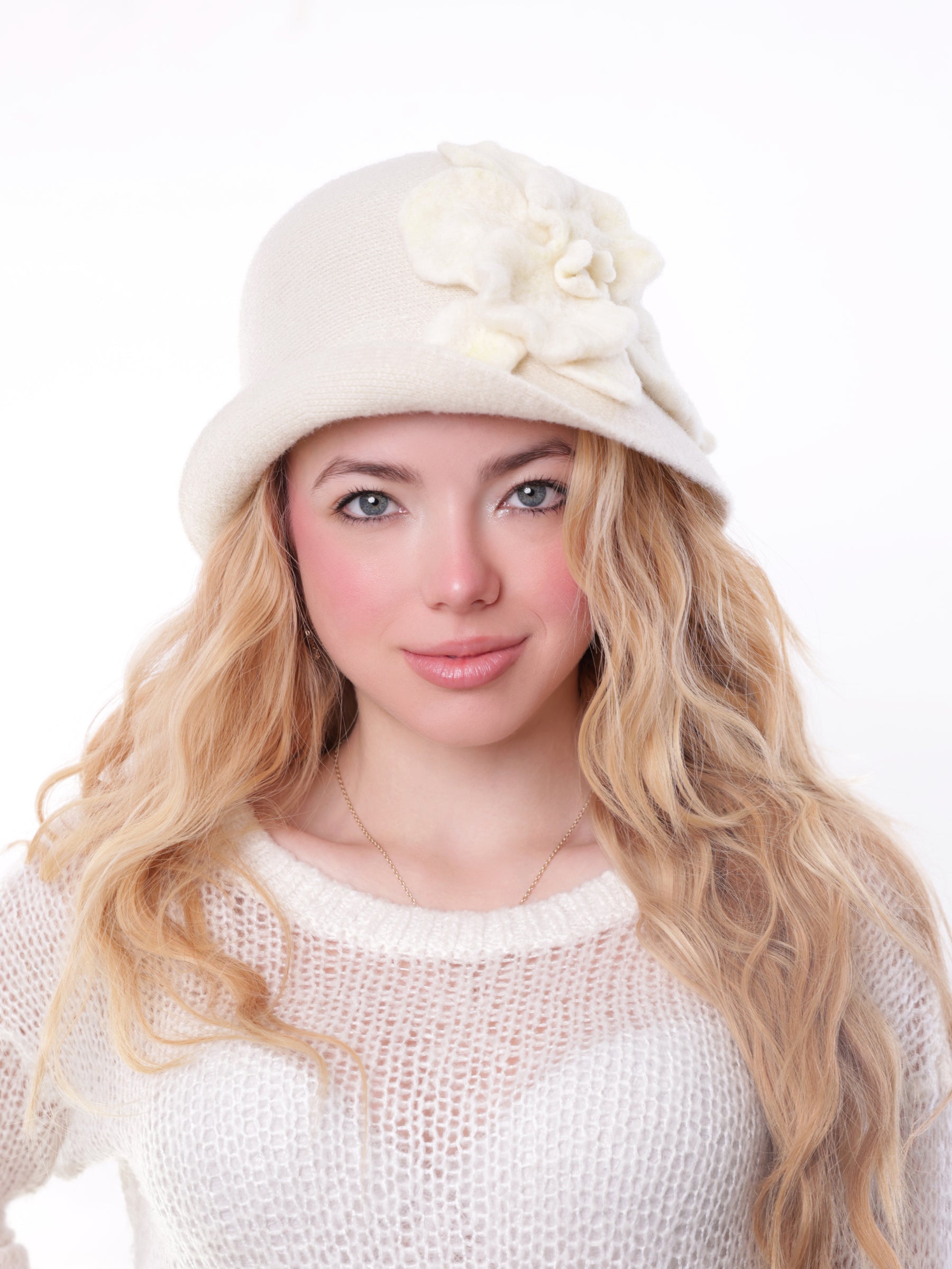 Woman wearing a handcrafted white wool cloche hat with a sculpted felt flower.