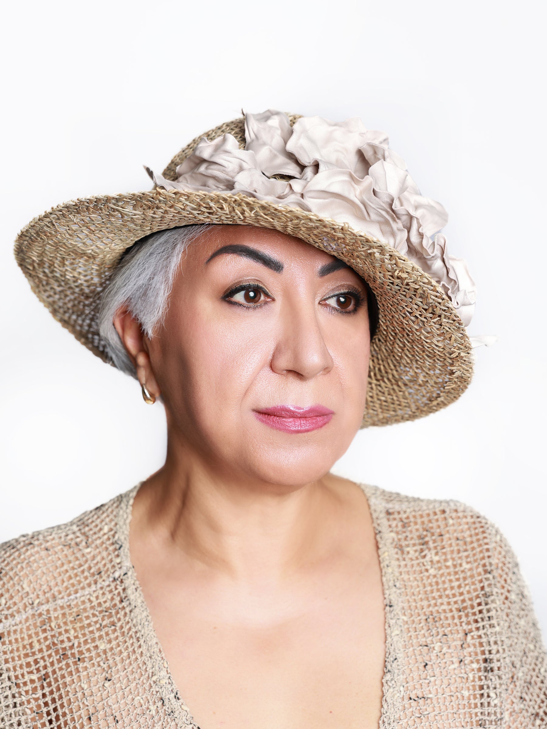 Side view of a woman wearing a handmade straw summer hat with a sculptural ivory satin flower.