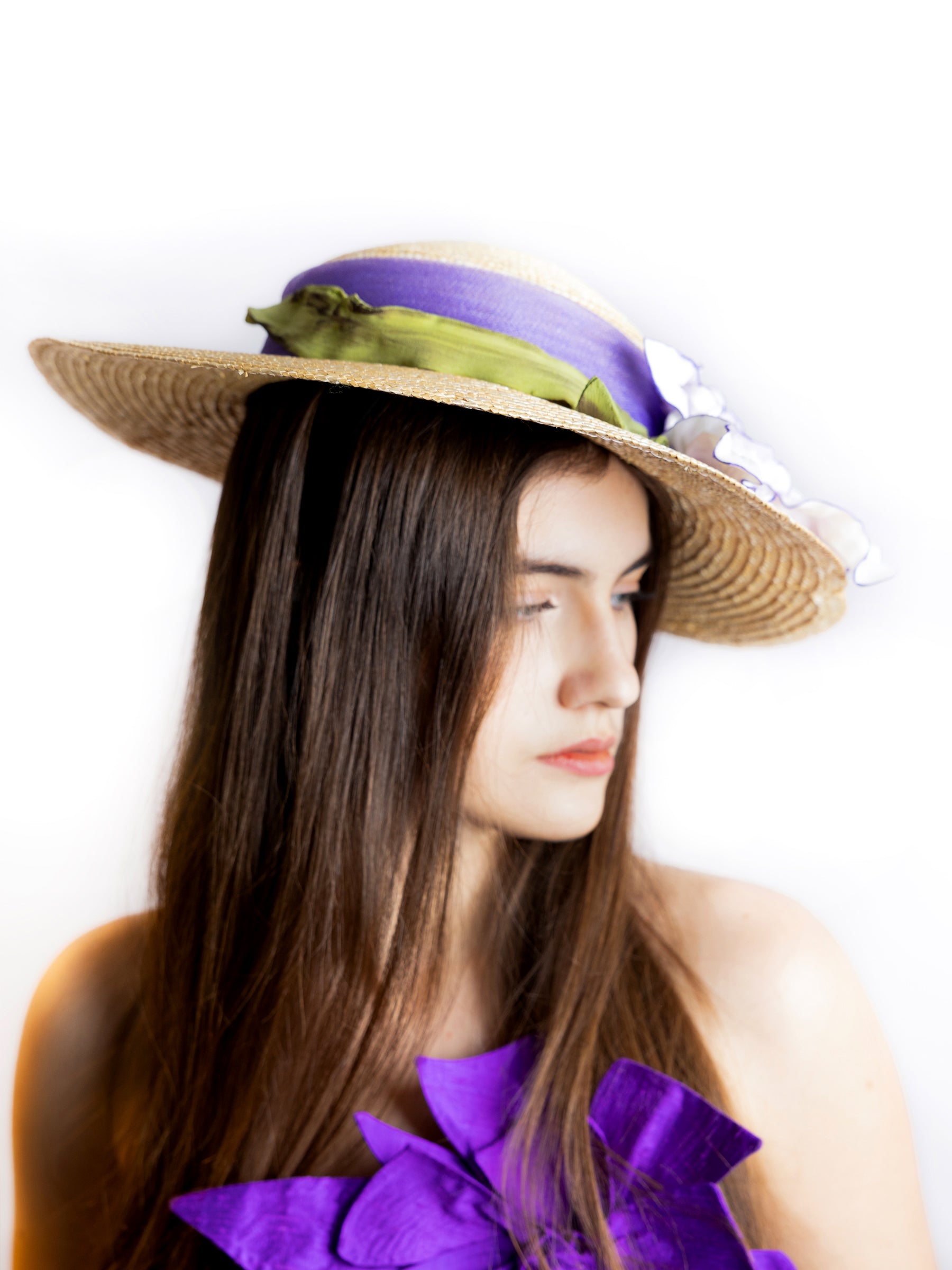 Side view of a straw wide-brim summer hat featuring satin floral details and ribbon accent.