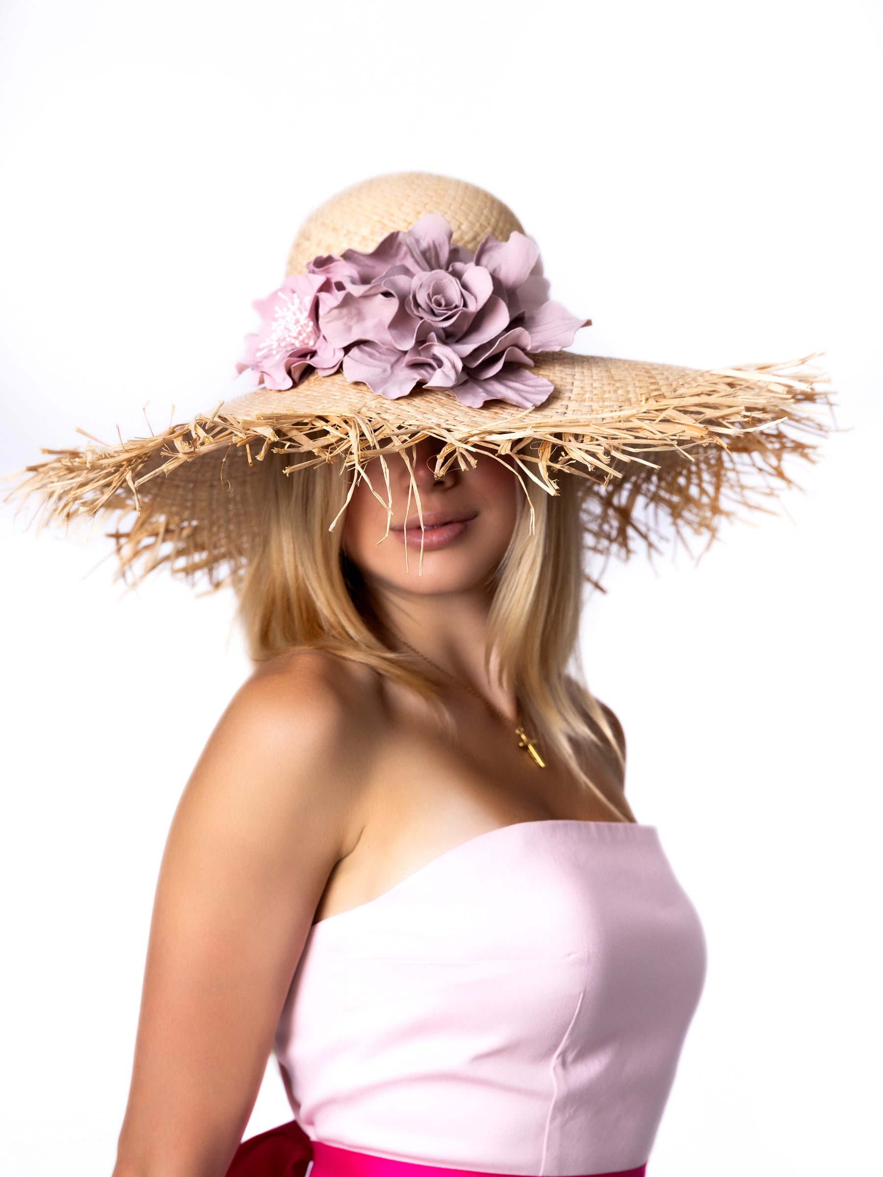 Close-up view of a straw summer sun hat highlighting the handmade pink satin flower.