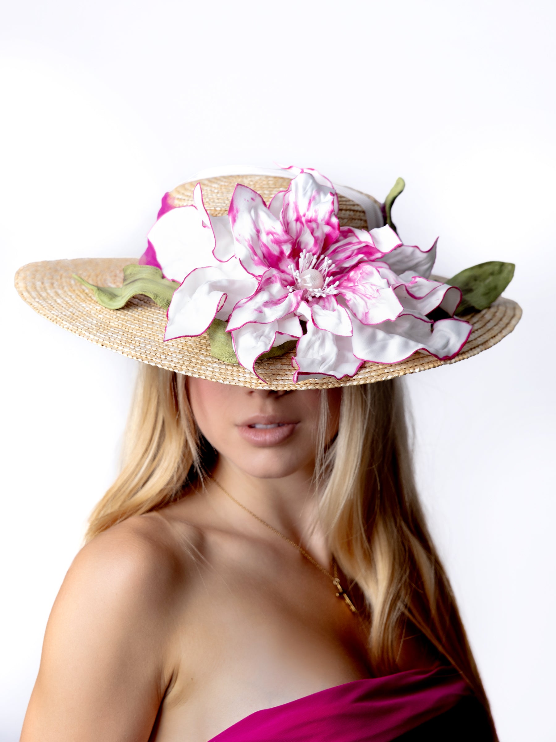 Top view of a straw summer hat showing handmade painted satin flower embellishments.