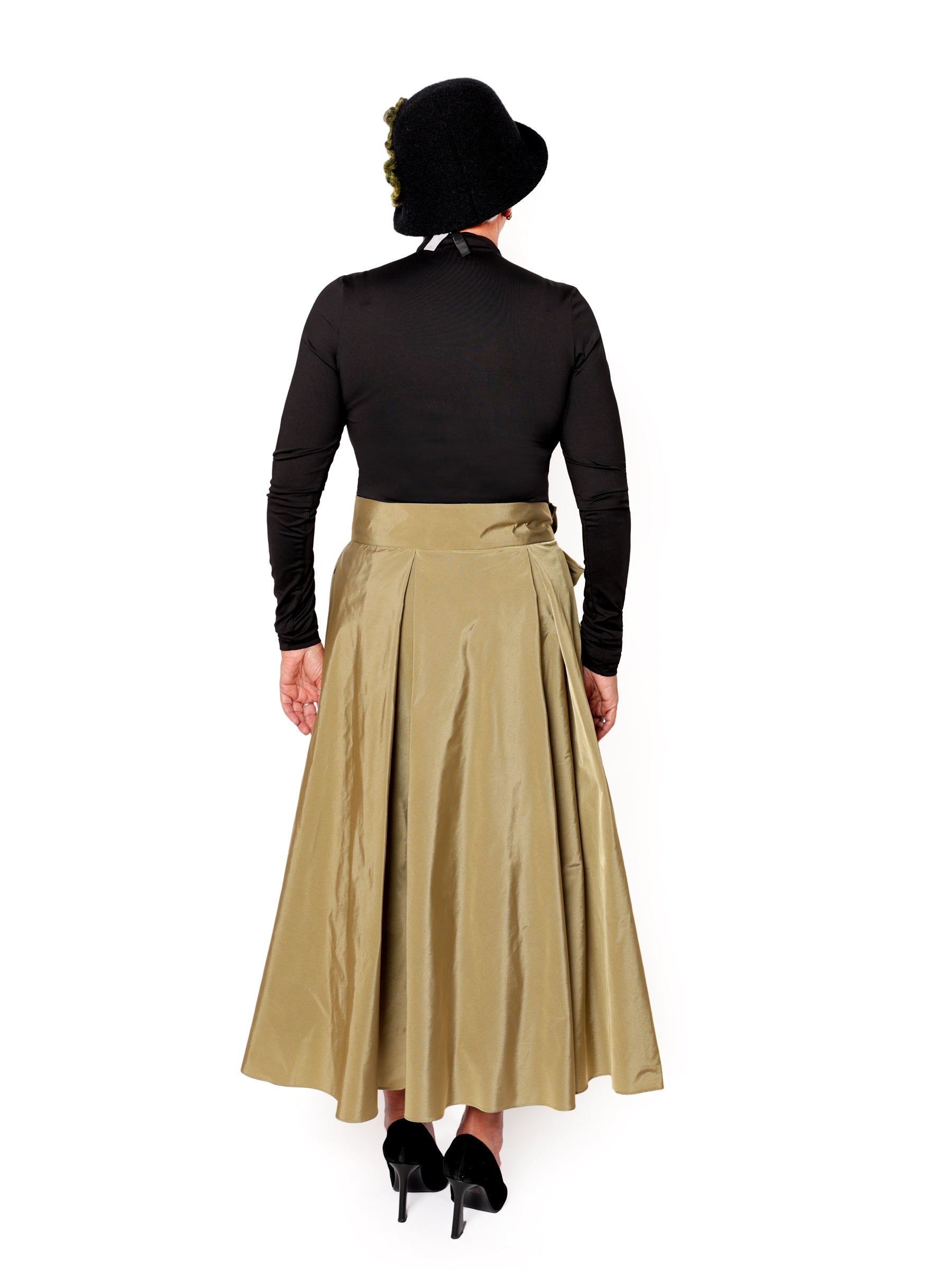 Back view of an olive green handcrafted midi skirt with flowing drape and sculptural silhouette, worn by a woman.