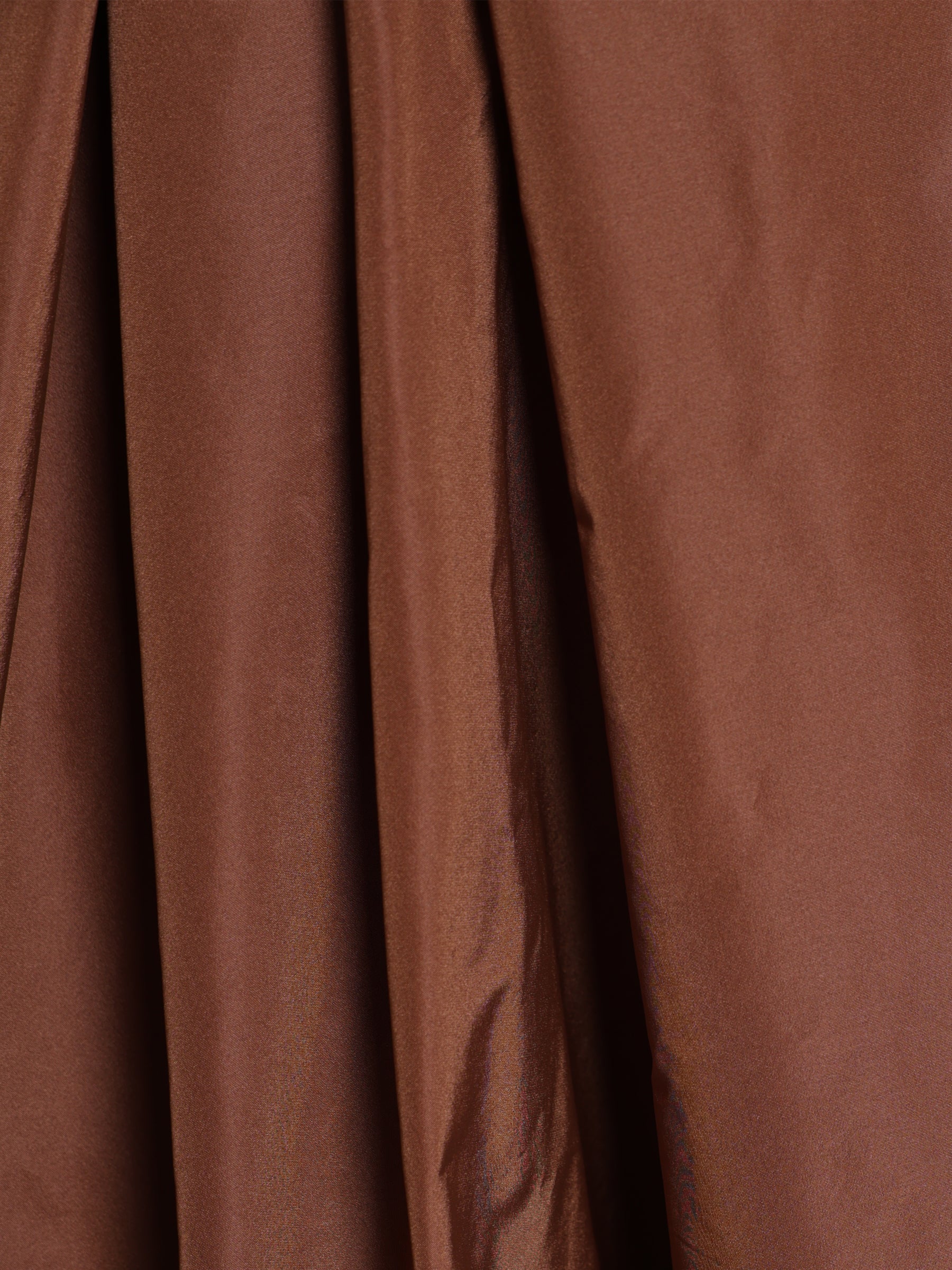 Close-up of copper brown woven fabric used in a midi skirt, showing texture and subtle sheen.