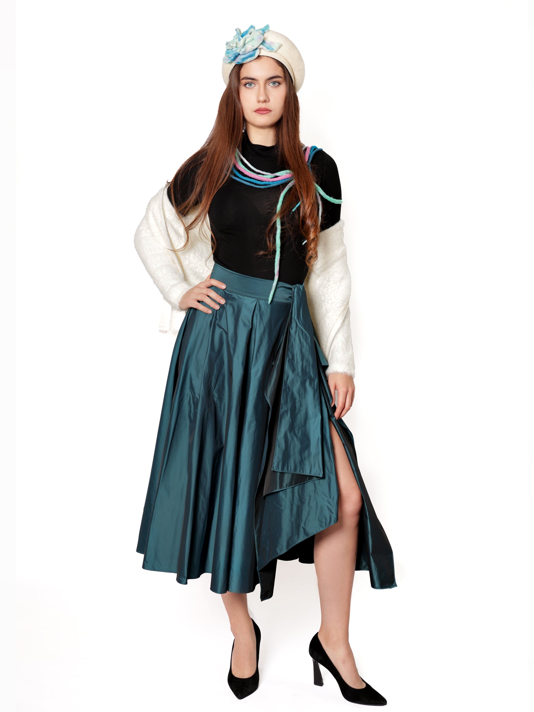 Woman wearing a handcrafted teal blue midi skirt with a fluid drape and elegant front slit.